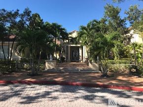 West Palm Beach condo for rent - A house entrance with a red brick pathway and palm trees.