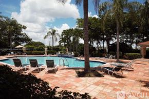 West Palm Beach condo for rent - A pool surrounded by chairs and trees.