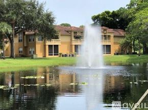 West Palm Beach condo for rent - A fountain in the middle of a pond in front of a building.