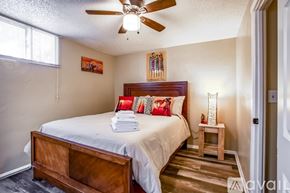 Denver apartment for rent - A bedroom with a bed, a ceiling fan, and a small table with a lamp.