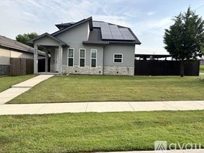 Fort Worth house for rent - A house with a grey roof and a solar panel on the roof is surrounded by a well-maintained lawn.