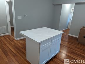 Fall River apartment for rent - A white kitchen island with a countertop and two doors is in a room with wooden floors.