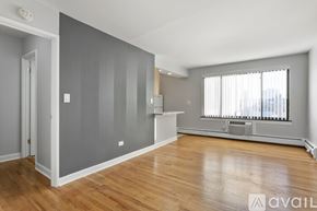 Chicago apartment for rent - A spacious room with wooden floors and a large window with blinds.