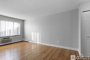 Chicago apartment for rent - A room with wooden floors and a window with blinds.