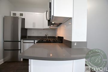 Chicago apartment for rent - A modern kitchen with white cabinets and a stainless steel refrigerator.
