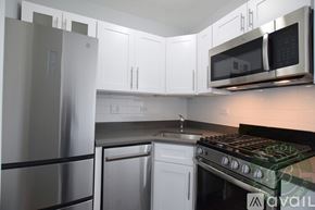 Chicago apartment for rent - A kitchen with a stainless steel refrigerator, white cabinets, and a black stove top.