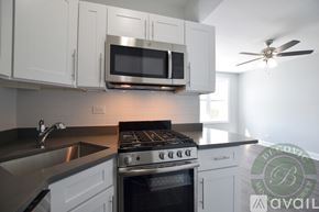 Chicago apartment for rent - A modern kitchen with a stove, microwave, and a fan.