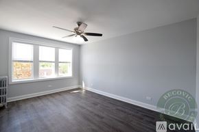 Chicago apartment for rent - A room with a ceiling fan and a window with a view of trees.
