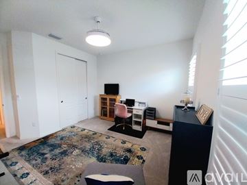 Bradenton house for rent - A living room with a rug, a sofa, a table with a lamp and a picture frame on it, and a cabinet with a TV on top.