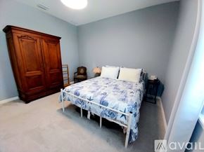Bradenton house for rent - A bedroom with a bed, a wooden armoire, and a nightstand with a lamp.
