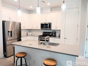 Bradenton house for rent - A kitchen with white cabinets and a stainless steel refrigerator.