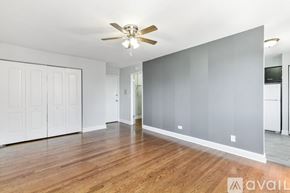 Chicago apartment for rent - A spacious room with a ceiling fan and wooden flooring.