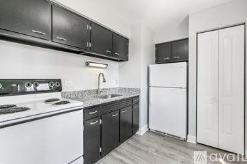 Chicago apartment for rent - A kitchen with black cabinets and a white refrigerator.