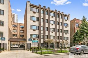 Chicago apartment for rent - A large brick building with a black fence in front.
