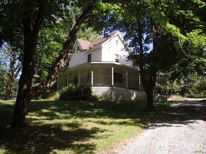 Ellicott City house for rent - A white house with a porch surrounded by trees.