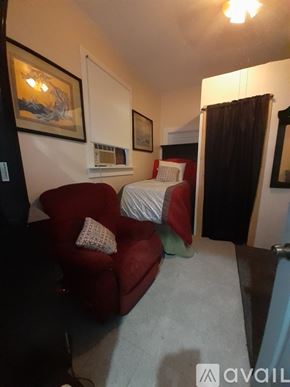 New Orleans apartment for rent - A room with a red chair and a bed with a white comforter.