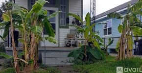 New Orleans apartment for rent - A house with a blue exterior is surrounded by green plants.