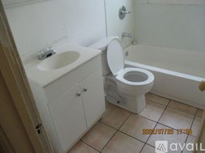 Detroit apartment for rent - A white toilet is in a bathroom with a sink and a bathtub.