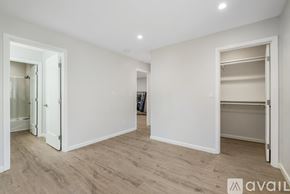 Oakland apartment for rent - A spacious room with white walls and wooden flooring, featuring a large open doorway and a built-in closet.