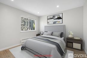 Oakland apartment for rent - A bedroom with a large bed and a window with a view of a cityscape.