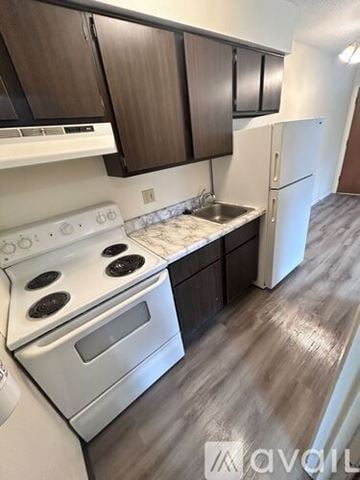 Iowa City apartment for rent - A kitchen with white appliances and brown cabinets.