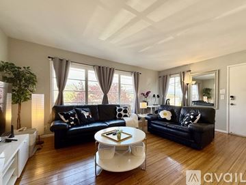 Richmond house for rent - A living room with black leather sofas and a white coffee table.