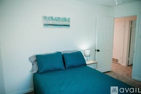 Jacksonville house for rent - A bedroom with a bed, two pillows, a nightstand with a lamp, and a painting on the wall.