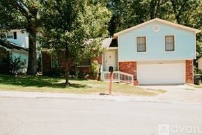 Jacksonville house for rent - A blue house with a white garage door is surrounded by trees.