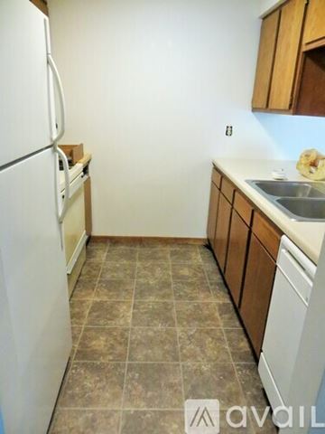 Minneapolis apartment for rent - A kitchen with a white fridge and brown cabinets.