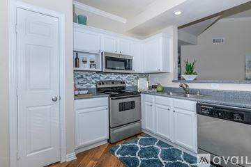 Lewisville apartment for rent - A kitchen with white cabinets and a patterned rug on the floor.