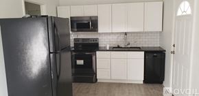 Natchitoches apartment for rent - A black refrigerator stands in a kitchen with white cabinets and a black dishwasher.