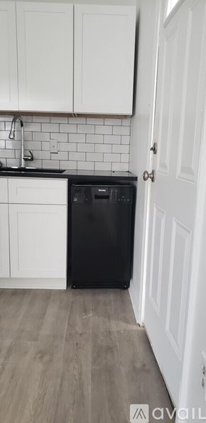 Natchitoches apartment for rent - A black trash bin sits in a kitchen next to a white door.