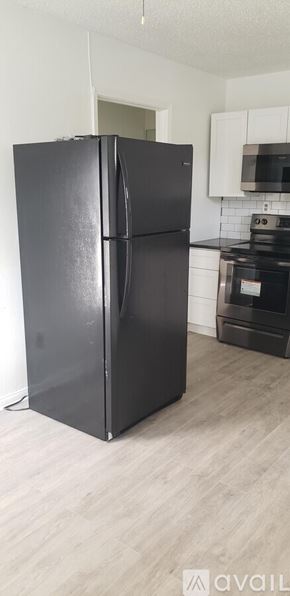 Natchitoches apartment for rent - A black refrigerator in a kitchen with wooden flooring.