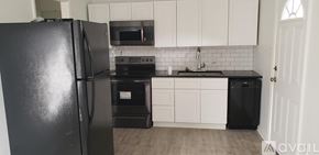 Natchitoches apartment for rent - A black refrigerator in a kitchen with white cabinets.