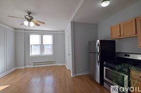 Chicago apartment for rent - A kitchen with a black fridge and wooden floors.