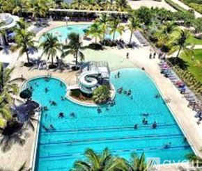 Surfside apartment for rent - A large swimming pool surrounded by palm trees.