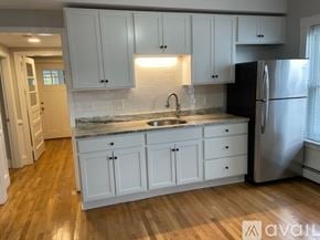 Worcester apartment for rent - A kitchen with white cabinets and a black refrigerator.