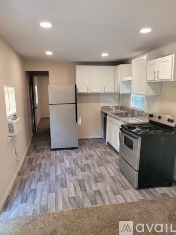 Livingston house for rent - A kitchen with a white fridge, stove, and cabinets.