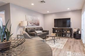 Shreveport townhouse for rent - A modern living room with a grey sofa, a wooden coffee table, and a flat screen TV mounted on the wall.