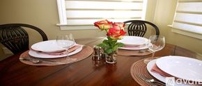 Norwalk apartment for rent - A dining table set with plates, glasses, and a vase of roses.