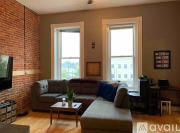 Stevens Point apartment for rent - A living room with a grey couch and a coffee table in front of a brick wall.