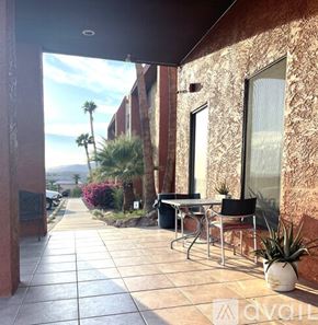 Bullhead City apartment for rent - A patio with a table and chairs overlooks a street with palm trees.