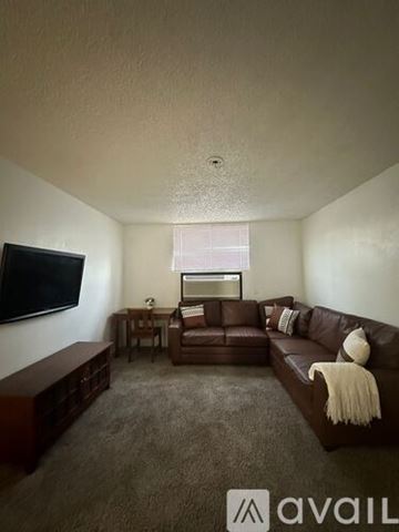 Bullhead City apartment for rent - A living room with a brown couch and a flat screen TV mounted on the wall.