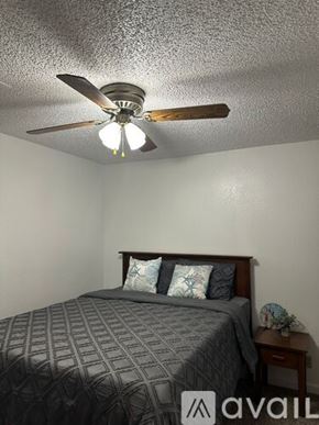 Bullhead City apartment for rent - A bedroom with a bed, pillows, a ceiling fan, and a nightstand.