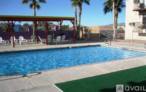 Bullhead City apartment for rent - A pool with a red roof and white chairs.