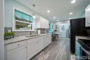 Tulsa house for rent - A kitchen with white cabinets and a black refrigerator.
