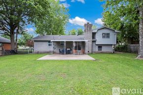 Tulsa house for rent - A house with a grey roof and a white chimney is surrounded by a green lawn and trees.