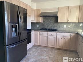 San Bruno apartment for rent - A kitchen with a black fridge and beige cabinets.