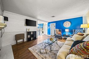 Tulsa house for rent - A living room with a white brick wall and a flat screen TV mounted above a wooden bench.