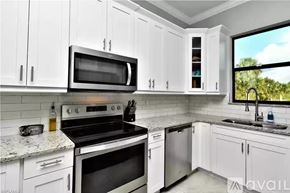 Naples apartment for rent - A kitchen with white cabinets and a black stove top oven.